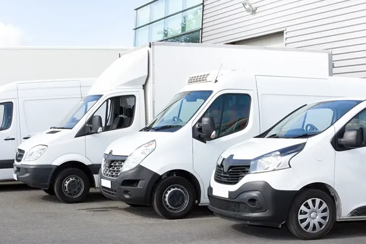 different types of coporate fleet vans and truck in a row in front of a business